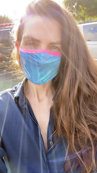 Front view of blue oil slick holographic face mask with pink blacklight trim with the full design visible